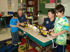 Capt Nicholas and Lt Hart with students and robotic arms used in demonstrations.